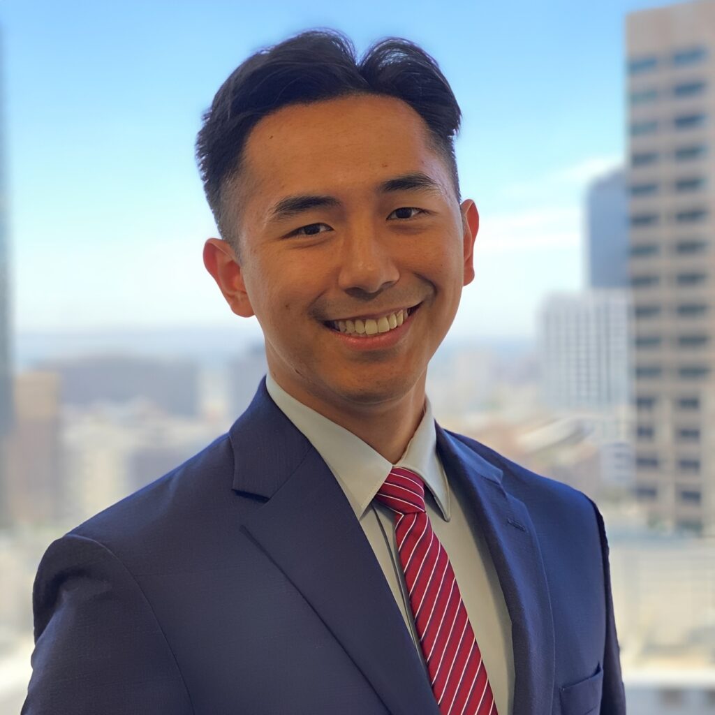 Smiling man in suit with city background.